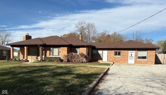 ranch-style home with brick siding, a shingled roof, fence, a front yard, and a chimney