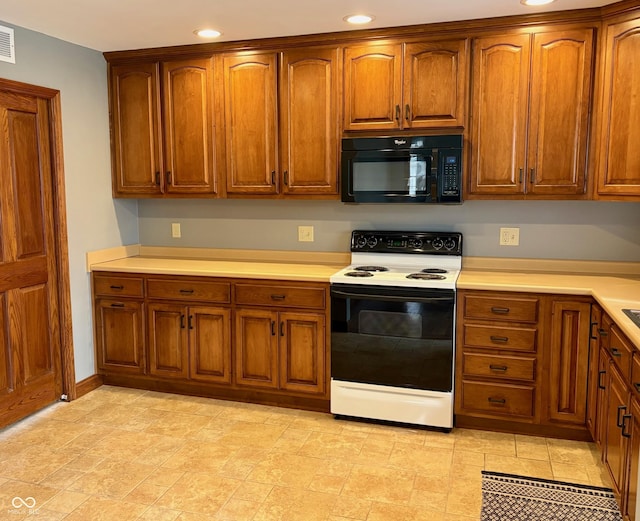 kitchen featuring electric range, brown cabinets, light countertops, and black microwave