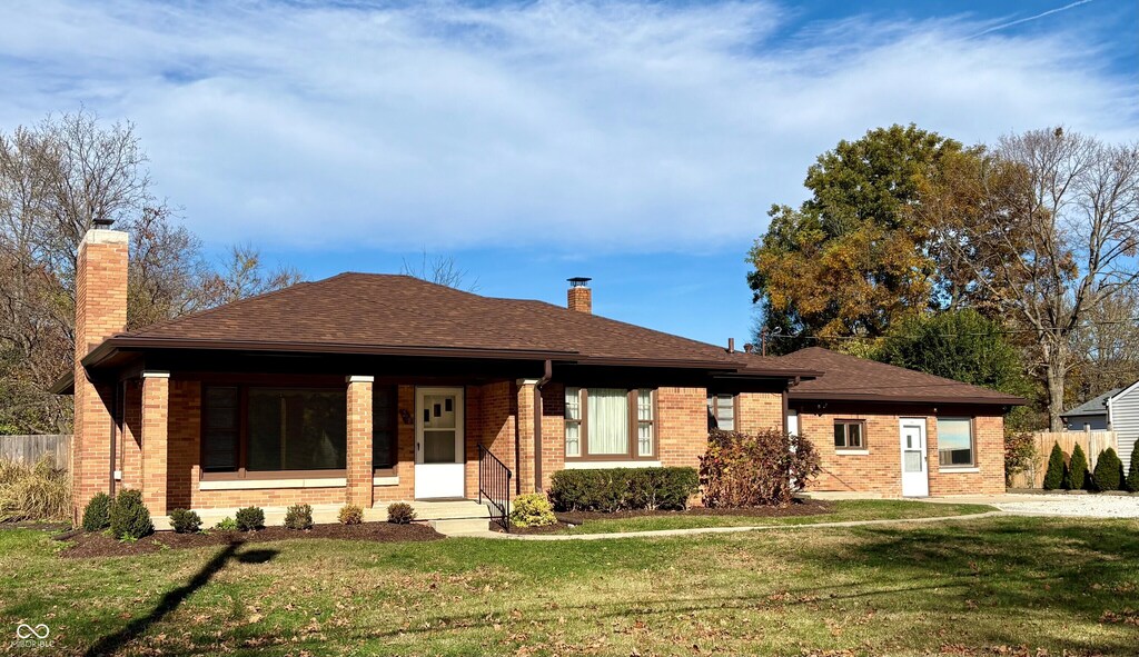 ranch-style home featuring a front yard, fence, brick siding, and a chimney