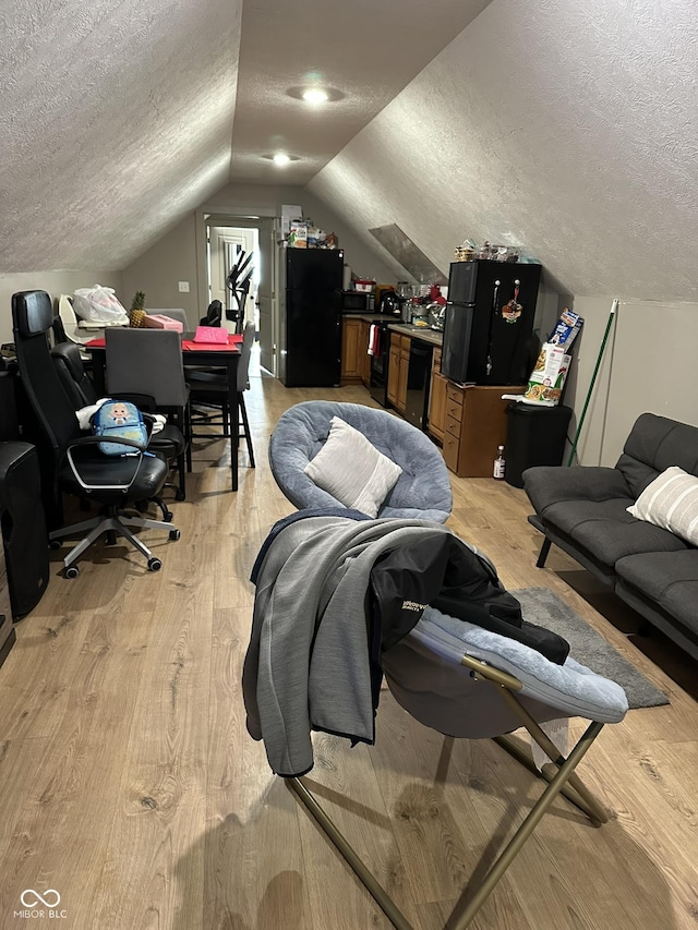 home office with vaulted ceiling, light wood-style flooring, and a textured ceiling