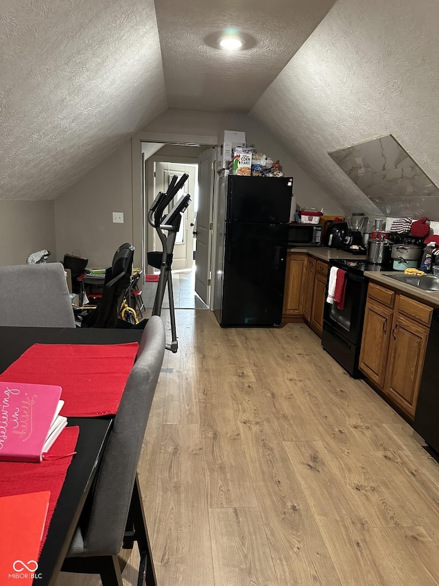 interior space with light wood-style flooring, a textured ceiling, lofted ceiling, and a sink