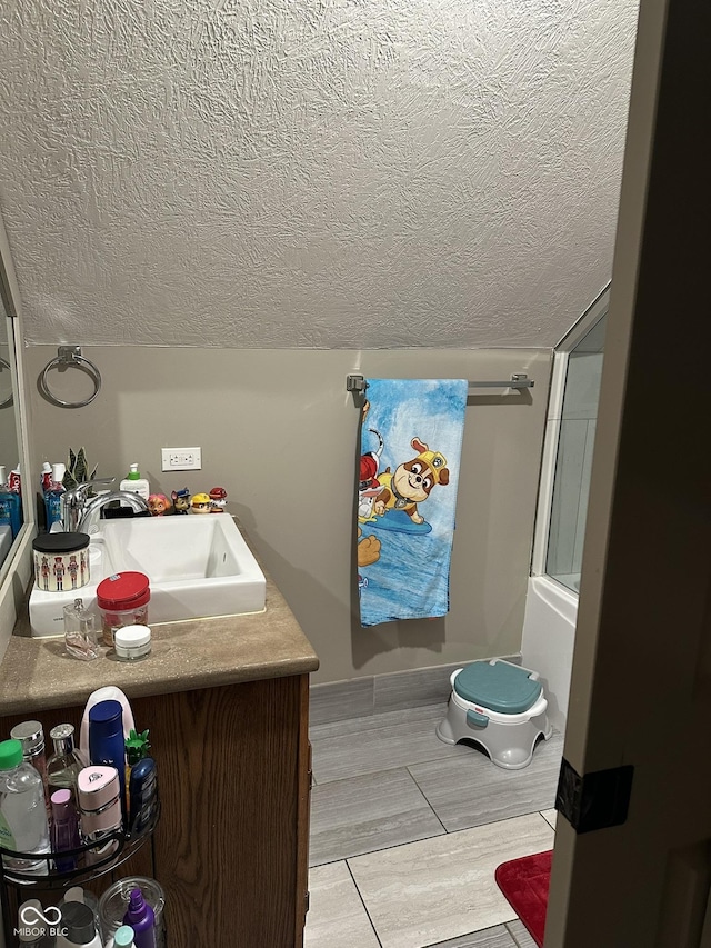 bathroom with wood tiled floor, lofted ceiling, a textured ceiling, and vanity