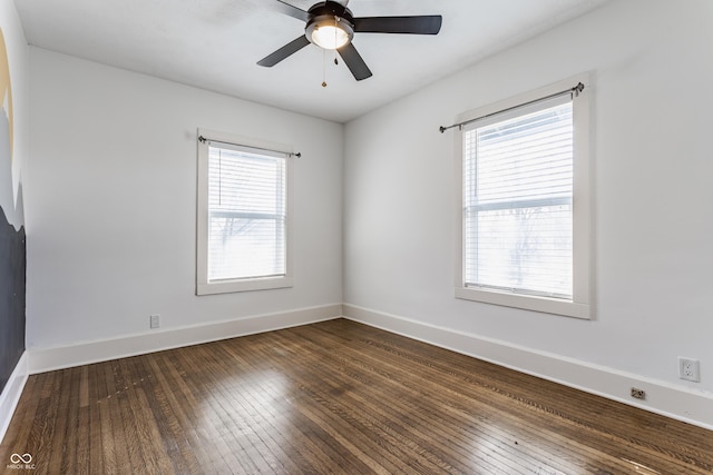 spare room featuring dark wood finished floors, plenty of natural light, baseboards, and ceiling fan