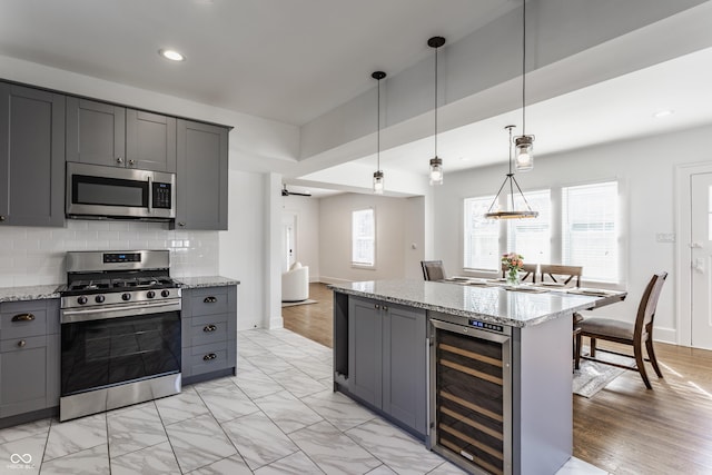 kitchen featuring wine cooler, decorative backsplash, gray cabinets, and stainless steel appliances