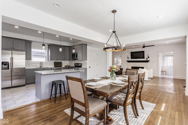 dining area with recessed lighting, ceiling fan, a fireplace, and light wood finished floors