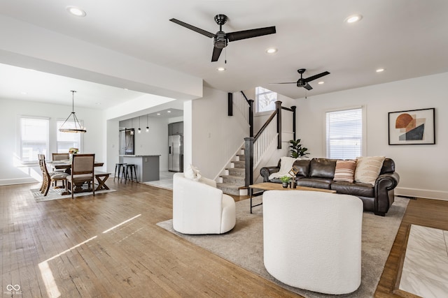 living area with stairway, plenty of natural light, and wood-type flooring