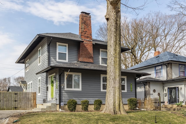 back of property with a shingled roof, fence, entry steps, a chimney, and a yard