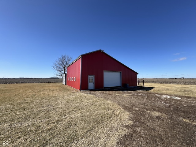 view of outdoor structure with an outbuilding, driveway, and a rural view