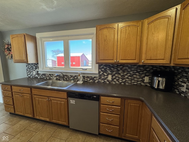 kitchen featuring dishwasher, backsplash, dark countertops, and a sink