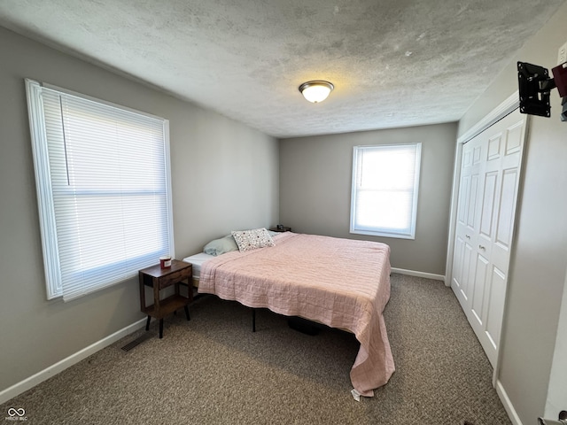 carpeted bedroom with a closet, a textured ceiling, and baseboards