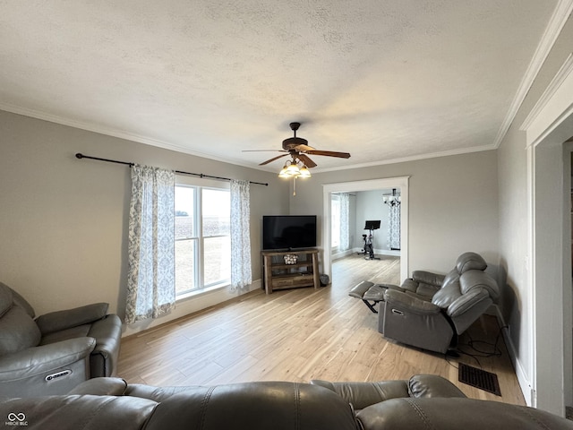 living area featuring visible vents, a ceiling fan, light wood-style flooring, crown molding, and a textured ceiling