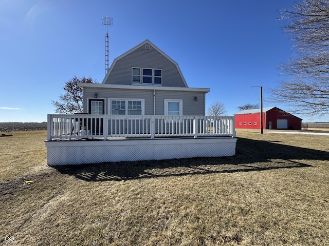 back of house featuring a deck, a detached garage, a gambrel roof, driveway, and a yard