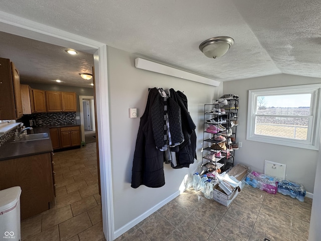 interior space featuring lofted ceiling, a sink, a textured ceiling, and baseboards