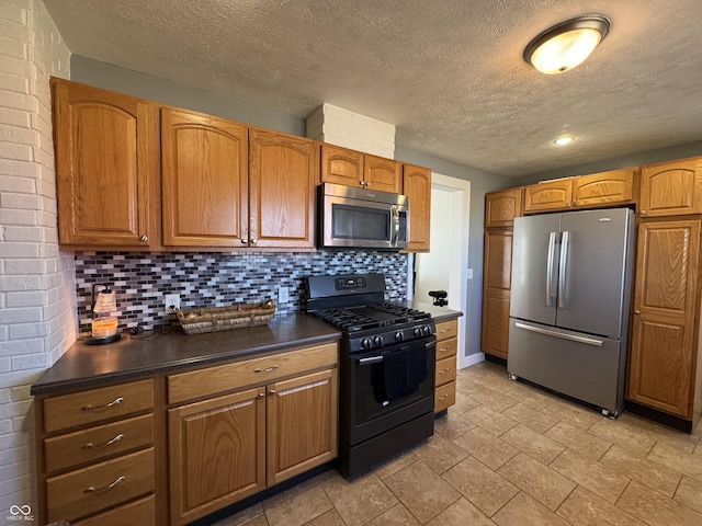 kitchen with appliances with stainless steel finishes, dark countertops, brown cabinets, and tasteful backsplash