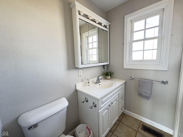 bathroom with tile patterned flooring, toilet, vanity, visible vents, and baseboards