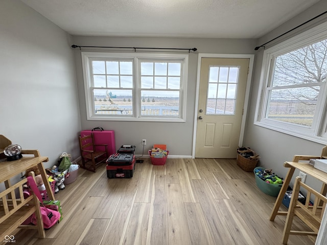 rec room with a textured ceiling, baseboards, and wood finished floors