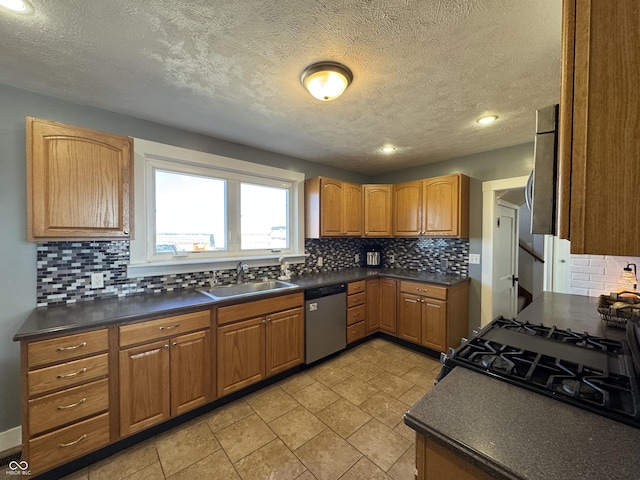 kitchen with dark countertops, dishwasher, a sink, and gas stove