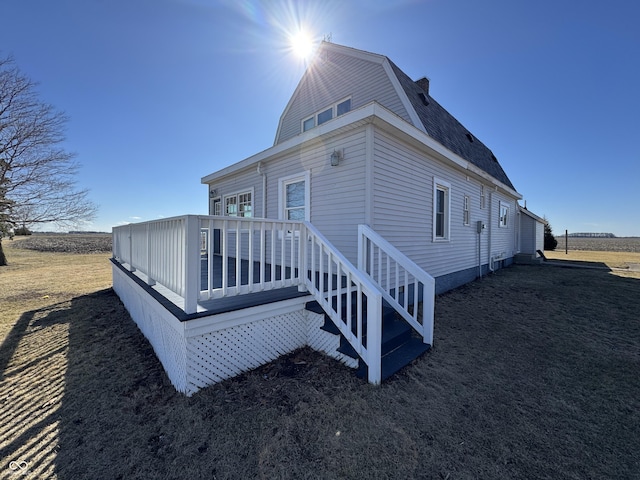 rear view of house with roof with shingles, a deck, and a gambrel roof