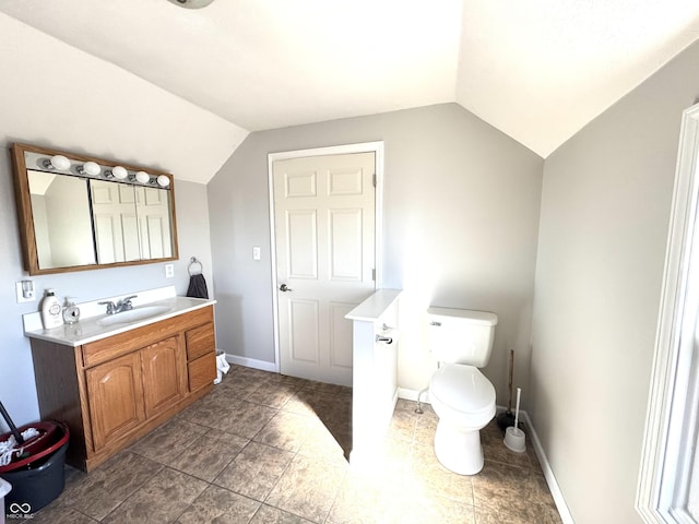 bathroom with toilet, baseboards, vaulted ceiling, and vanity