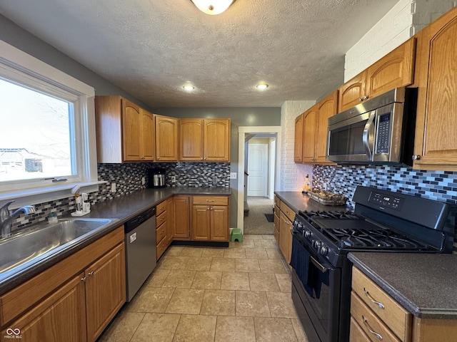 kitchen with appliances with stainless steel finishes, dark countertops, a sink, and tasteful backsplash