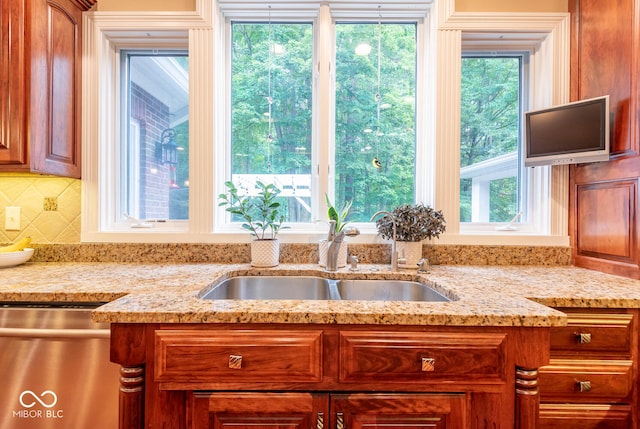 kitchen featuring dishwasher, light stone countertops, tasteful backsplash, and a sink