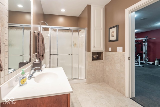 bathroom with tile patterned floors, a shower stall, vanity, and tile walls