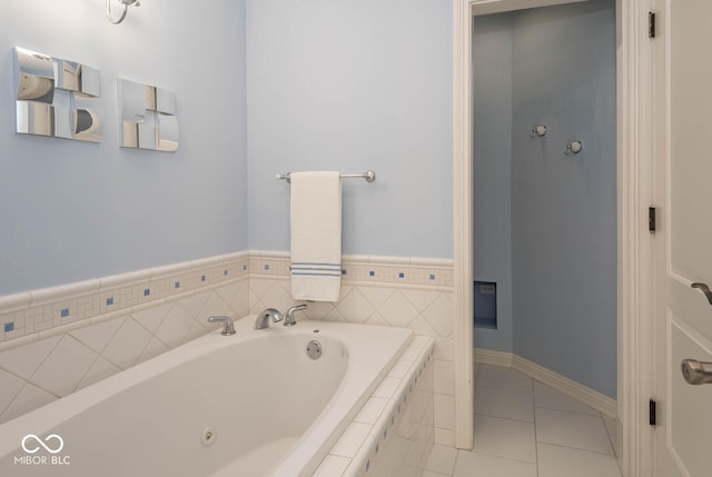 bathroom featuring tile patterned floors, a tub with jets, and baseboards