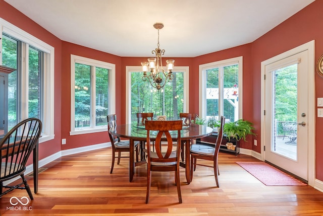 dining room with light wood finished floors, a chandelier, baseboards, and a wealth of natural light