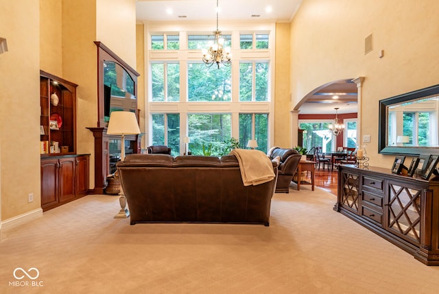 living room featuring decorative columns, arched walkways, a high ceiling, and an inviting chandelier