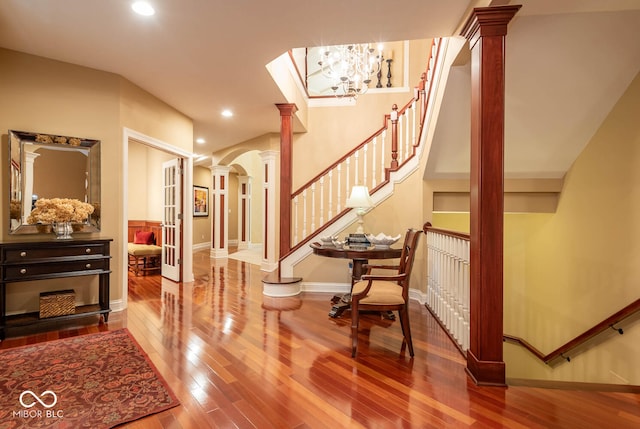 foyer entrance with stairway, arched walkways, wood finished floors, and ornate columns