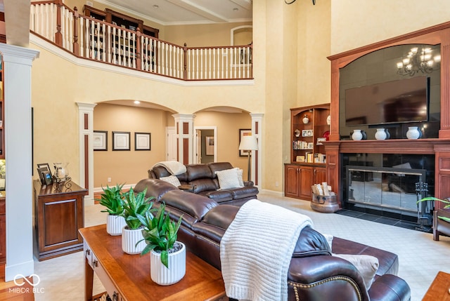 living room with a fireplace with flush hearth, arched walkways, decorative columns, baseboards, and a towering ceiling