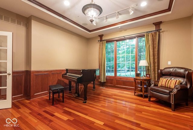 sitting room featuring wainscoting, rail lighting, a tray ceiling, and wood finished floors