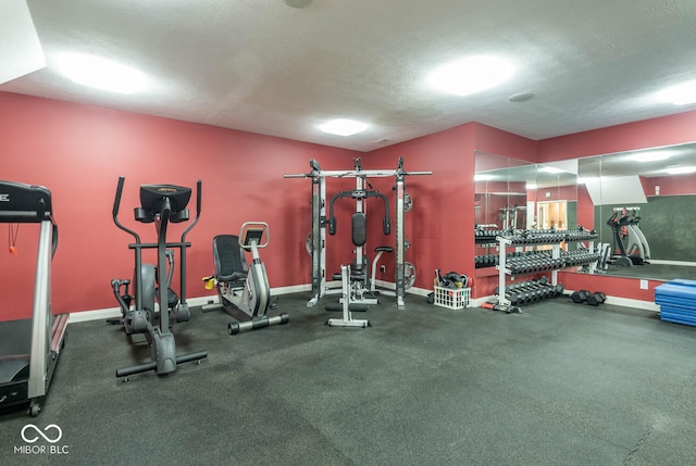 exercise room with baseboards and a textured ceiling