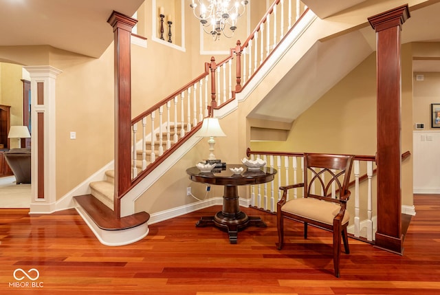 stairway featuring baseboards, ornate columns, and wood finished floors