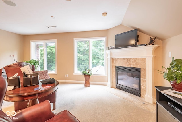 carpeted living area featuring a tiled fireplace, visible vents, baseboards, and lofted ceiling