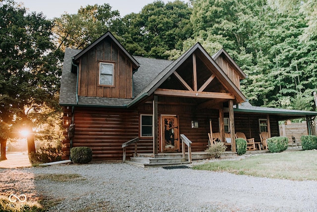 log cabin with log exterior, a porch, and roof with shingles