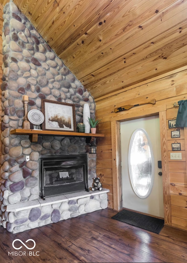 foyer entrance with wood finished floors, wood walls, a fireplace, wood ceiling, and vaulted ceiling