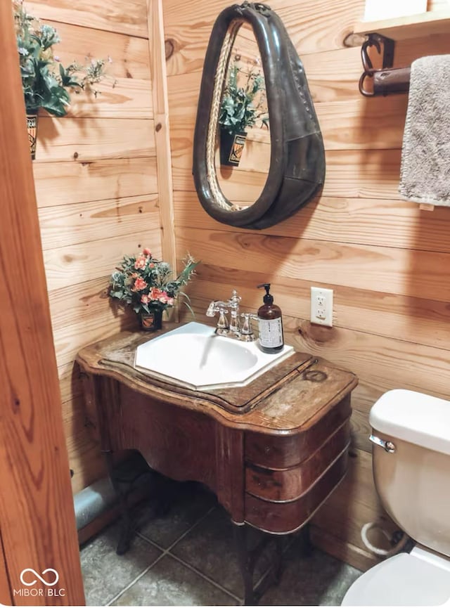 bathroom with vanity, toilet, wooden walls, and tile patterned flooring