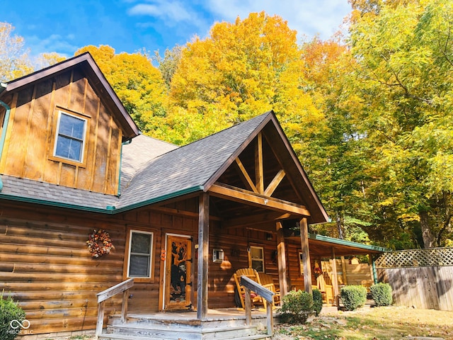 log-style house featuring covered porch, board and batten siding, and roof with shingles