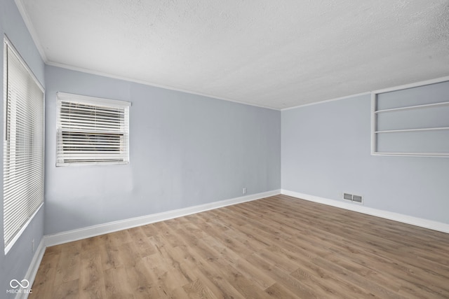 spare room featuring visible vents, a textured ceiling, baseboards, and wood finished floors