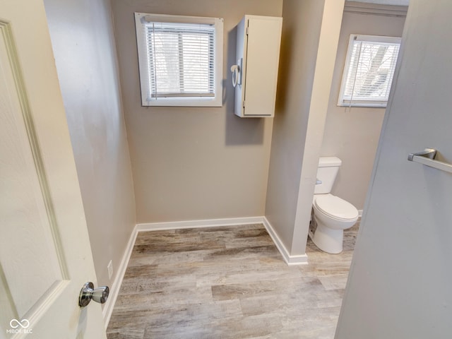 bathroom with toilet, wood finished floors, baseboards, and a wealth of natural light