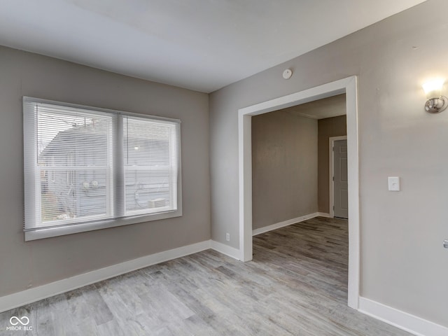 spare room with baseboards and light wood finished floors