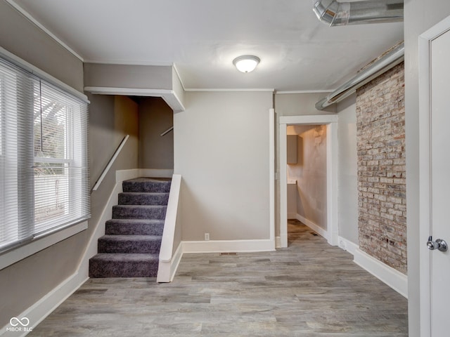 interior space with stairs, crown molding, wood finished floors, and baseboards