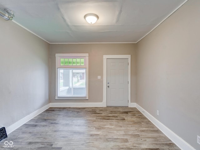 foyer entrance featuring wood finished floors, baseboards, and ornamental molding