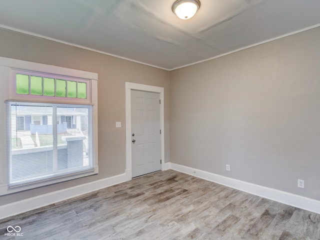 spare room with crown molding, baseboards, and wood finished floors