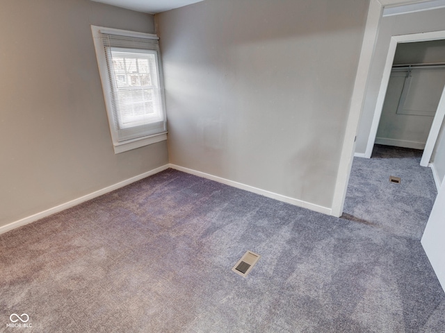 interior space featuring a closet, visible vents, dark carpet, and baseboards