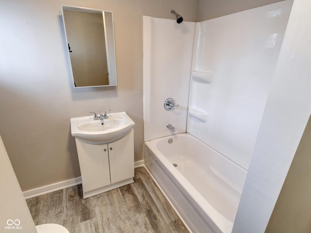 bathroom featuring vanity, wood finished floors, tub / shower combination, and baseboards