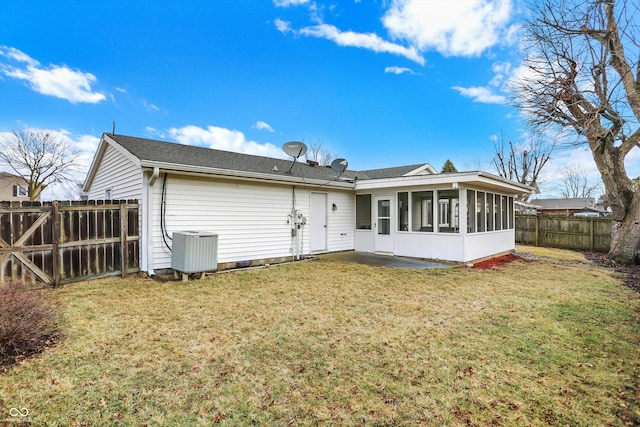 rear view of property featuring a sunroom, a fenced backyard, cooling unit, and a yard