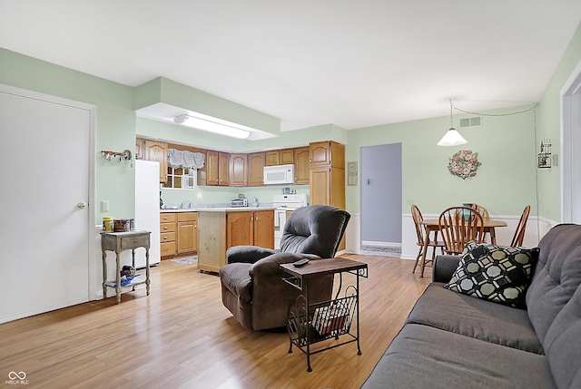 living area with visible vents, light wood-style flooring, and baseboards