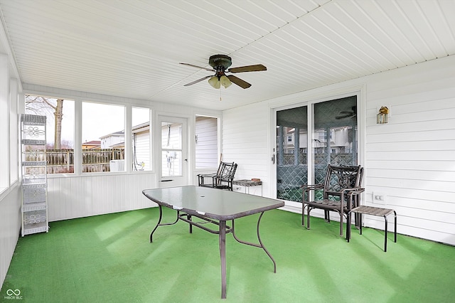 exterior space with carpet floors, wood walls, and a ceiling fan